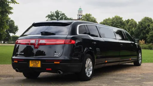 Rear three quarter view of black Lincoln MKT limousine with wraparound tail lights and extended stretch body.
