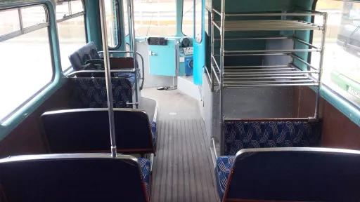 Lower deck interior of a vintage Leyland double decker bus with traditional bench seating and aisle.