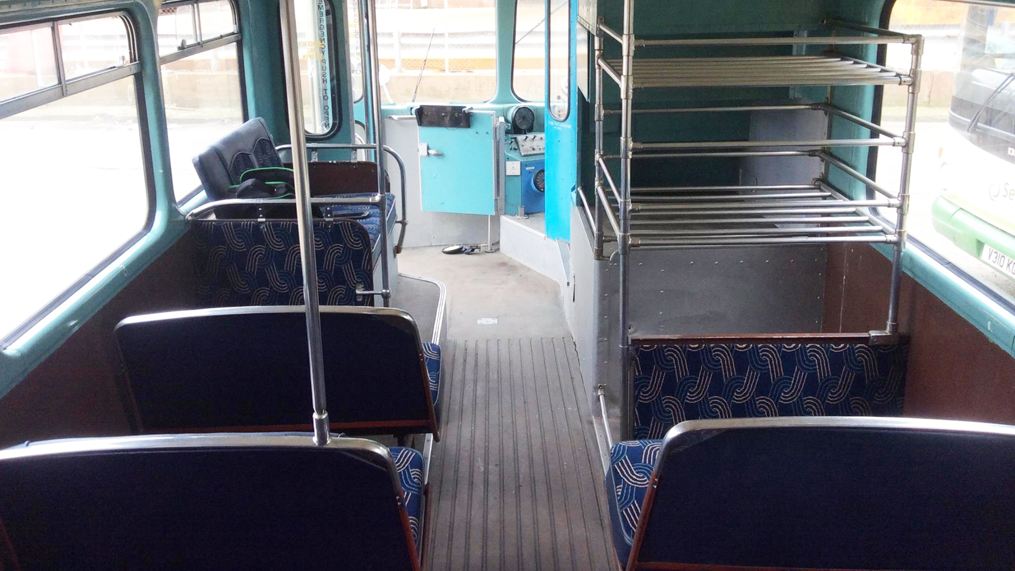 Lower deck interior of a vintage Leyland double decker bus with traditional bench seating and aisle.