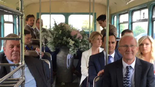 Wedding guests seated inside the lower deck of a cream vintage Leyland double decker bus.