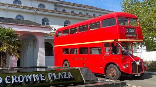 Red Routemaster double decker wedding bus parked outside the Crowne Plaza hotel entrance.