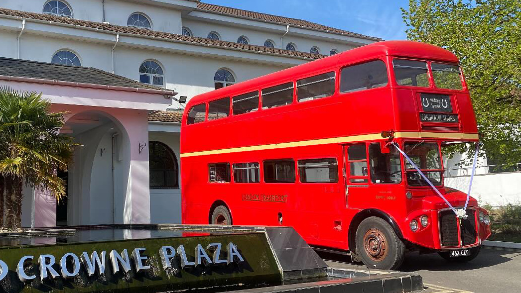Red Routemaster double decker wedding bus parked outside the Crowne Plaza hotel entrance.
