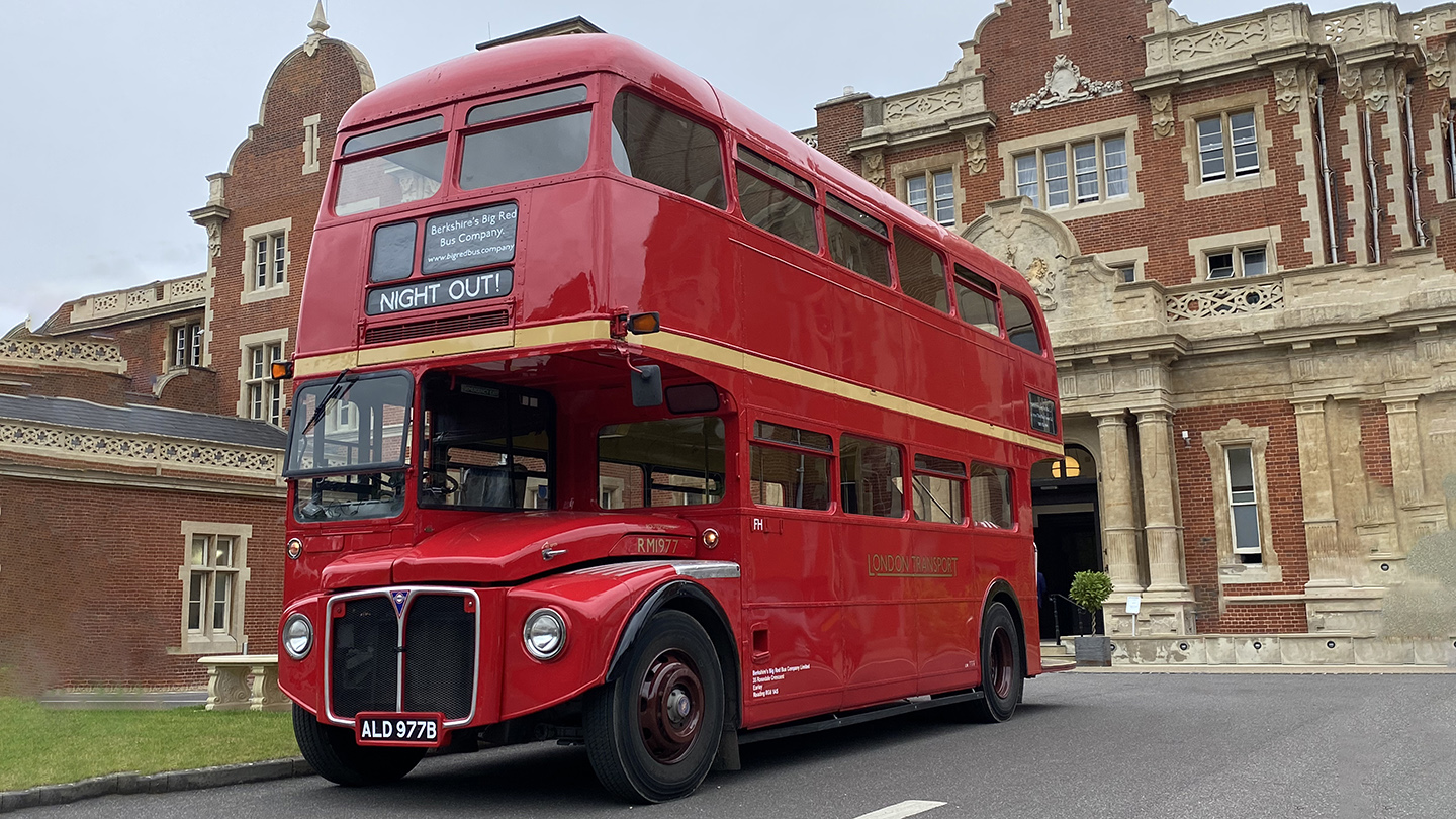 Red vintage Routemaster double decker bus parked outside a large heritage building used for weddings.