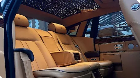Interior of a Rolls-Royce Phantom Series II EWB showing cream leather rear seating, luxury centre console and illuminated starlight headliner.