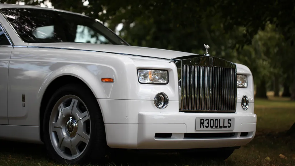 Front detail of a white Rolls-Royce Phantom featuring the iconic chrome radiator grille, Spirit of Ecstasy bonnet ornament and chrome trim.