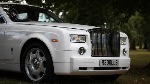 Front detail of a white Rolls-Royce Phantom featuring the iconic chrome radiator grille, Spirit of Ecstasy bonnet ornament and chrome trim.