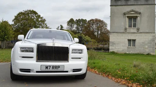 Front view of a white Rolls-Royce Phantom Series II luxury wedding car showing the iconic chrome radiator grille, Spirit of Ecstasy bonnet ornament and elegant styling.