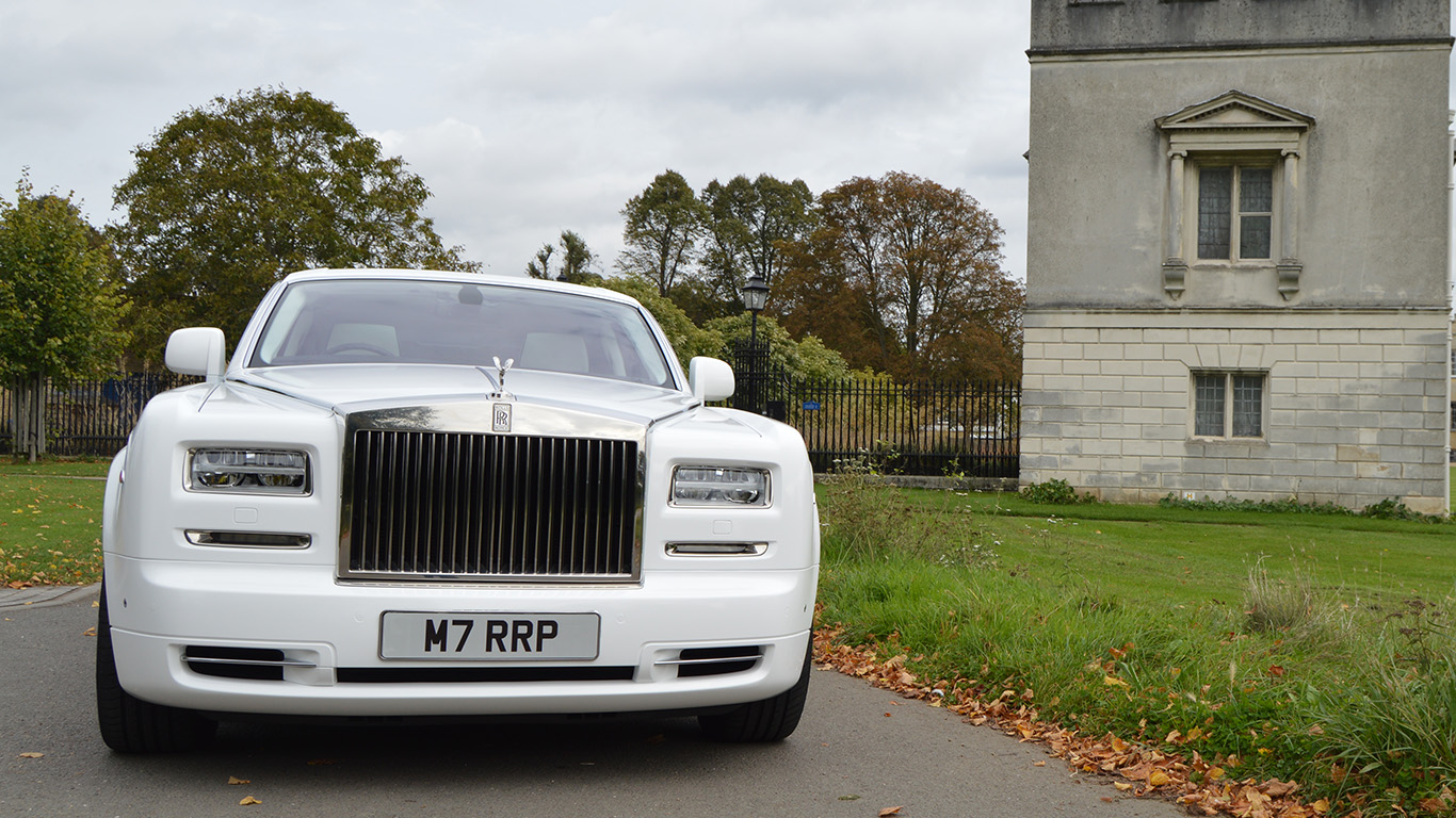 Front view of a white Rolls-Royce Phantom Series II luxury wedding car showing the iconic chrome radiator grille, Spirit of Ecstasy bonnet ornament and elegant styling.