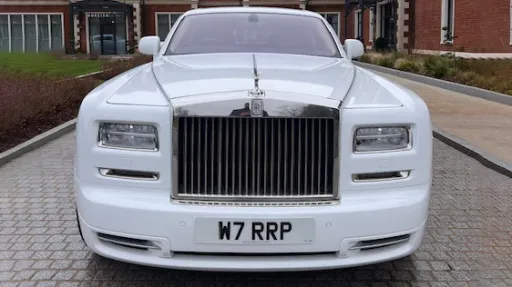 Full front view of a white Rolls-Royce Phantom Series II Extended Wheelbase wedding car featuring the iconic chrome radiator grille and Spirit of Ecstasy bonnet ornament parked on a driveway.