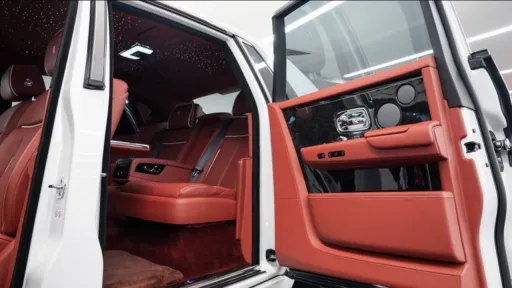 White Rolls-Royce Phantom VIII wedding car with grey bonnet and rear coach door open, revealing red leather interior and luxury passenger compartment.