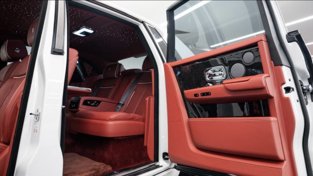 White Rolls-Royce Phantom VIII wedding car with grey bonnet and rear coach door open, revealing red leather interior and luxury passenger compartment.