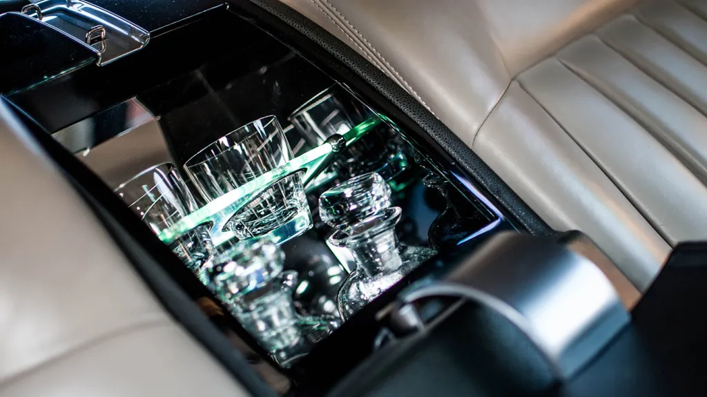 Luxury rear centre armrest inside Rolls-Royce Phantom showing integrated crystal glasses and polished interior detailing.