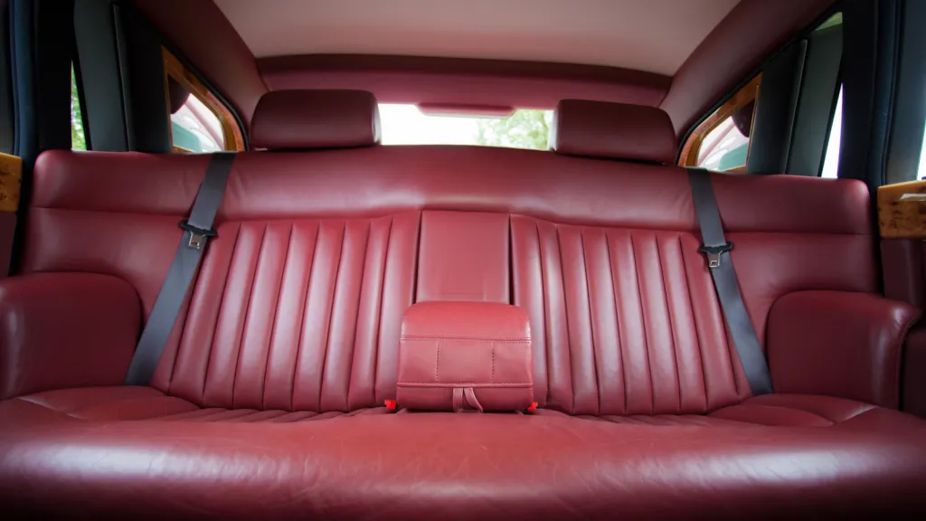 Rear passenger seating inside Rolls-Royce Phantom featuring burgundy leather seats, centre armrest and spacious luxury interior.