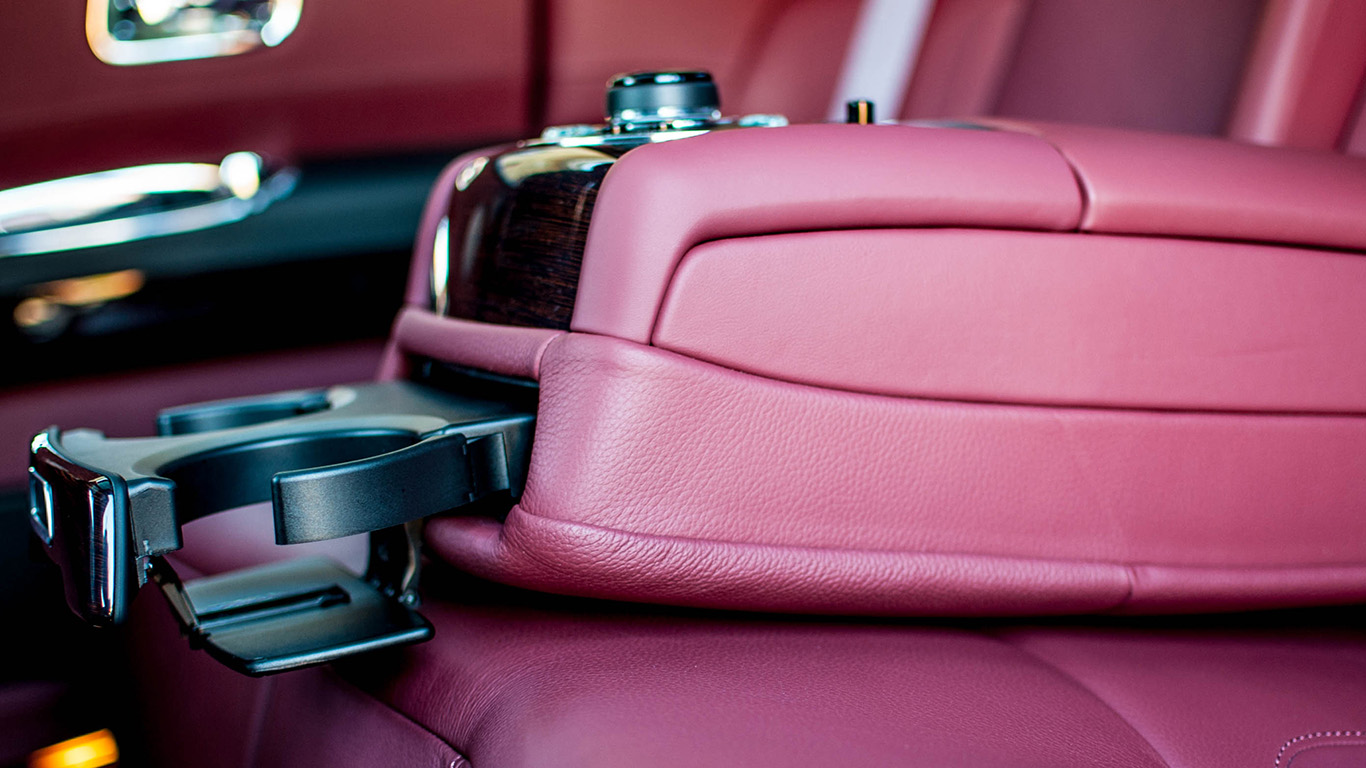 Rear passenger seating of Rolls-Royce Ghost featuring burgundy leather seats, luxury armrest and refined interior trim.