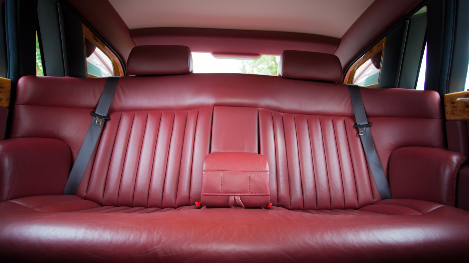 Rear passenger seating inside Rolls-Royce Phantom featuring burgundy leather seats, centre armrest and spacious luxury interior.