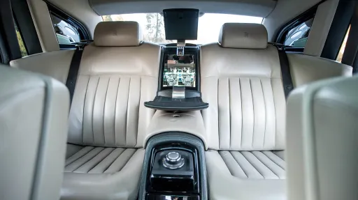 Rear passenger seating of Rolls-Royce Phantom featuring cream leather seats, centre console and spacious luxury cabin.