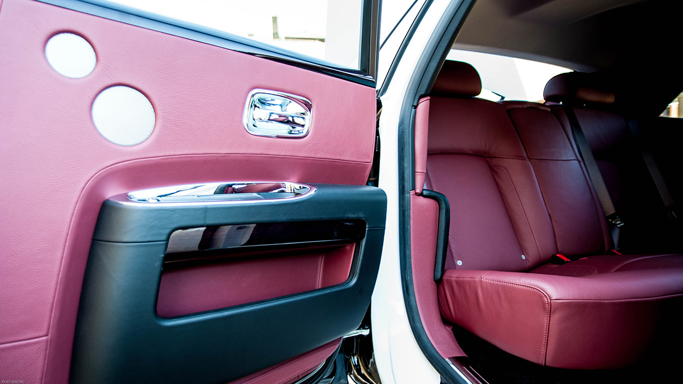 Rear interior of Rolls-Royce Ghost showing burgundy leather seating and rear coach door open for passenger entry.