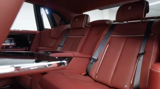 Rear passenger seating inside Rolls-Royce Phantom VIII featuring red leather seats, centre armrest and luxury handcrafted interior trim.