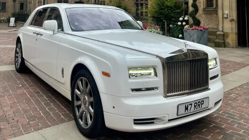 White Rolls-Royce Phantom Series II luxury wedding car with chrome grille and alloy wheels parked on a brick driveway in the City of London.