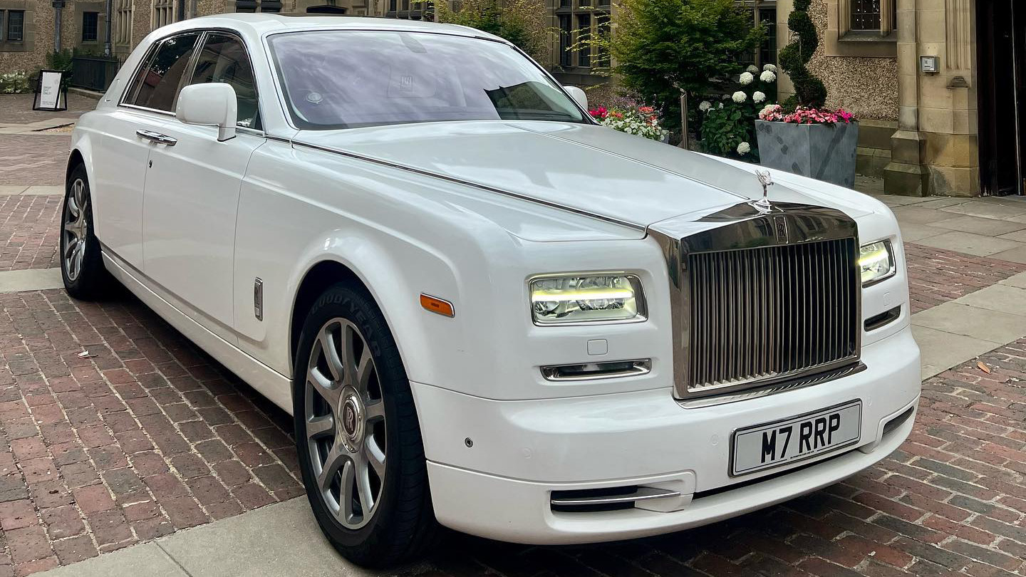 White Rolls-Royce Phantom Series II luxury wedding car with chrome grille and alloy wheels parked on a brick driveway in the City of London.