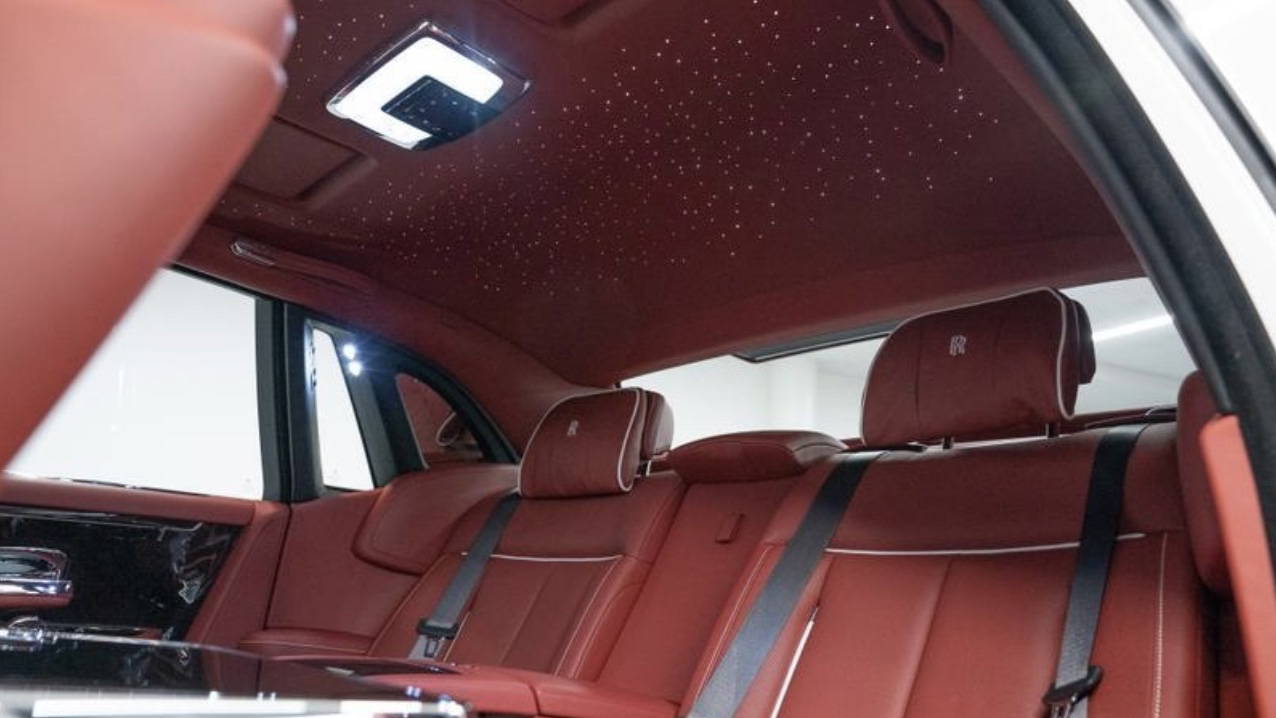 Rolls-Royce Phantom VIII interior showing the illuminated starlight headliner above red leather rear seats and luxury cabin trim.