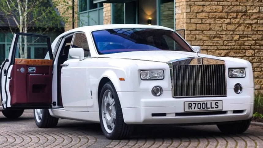 White Rolls-Royce Phantom luxury wedding car with rear coach door open revealing burgundy leather interior and spacious passenger compartment.