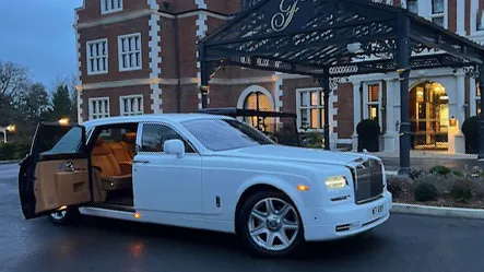 White Rolls-Royce Phantom Series II Extended Wheelbase wedding car with rear coach door open revealing cream leather interior and spacious passenger compartment outside a hotel entrance.