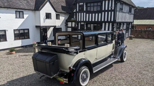 Bramwith Landaulette limousine with rear convertible roof open, black and ivory bodywork parked on gravel courtyard.