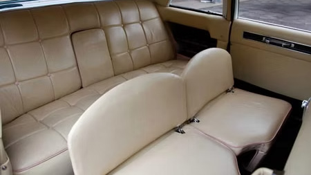 Cream leather interior of Cadillac limousine showing bench seating, door panel and spacious rear cabin layout.