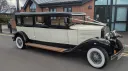 Side profile of black and ivory Bramwith limousine parked on road, showing long body and classic vintage styling.