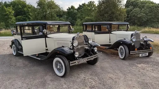 Two identical black and ivory Bramwith limousines parked side by side, vintage wedding cars with matching styling.