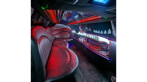 Inside Lincoln stretch limousine showing black leather wraparound seating with colourful LED lighting and illuminated bar area.