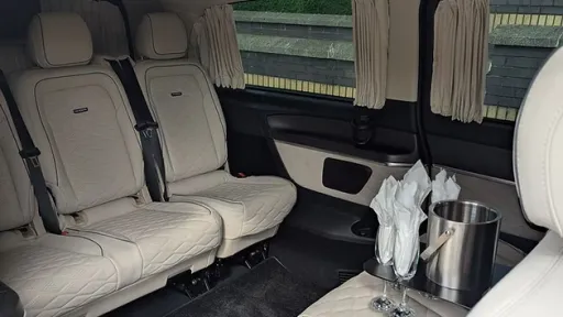 Rear cabin of Mercedes V-Class showing cream leather seats, individual seating layout with privacy glass and ambient lighting.