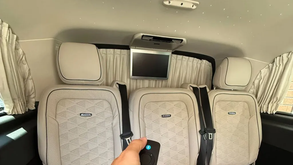 Cream leather interior of Mercedes V-Class with three individual rear seats, spacious cabin and soft lighting.