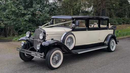 Black and ivory Bramwith Landaulette 7-seater limousine parked on driveway, showing vintage styling and cream interior.