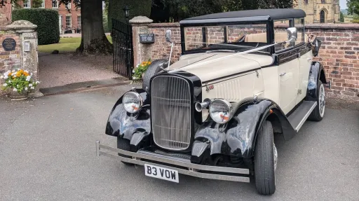 Front view of black and ivory Cowley vintage limousine with chrome grille, white wall tyres and classic 1930s styling.