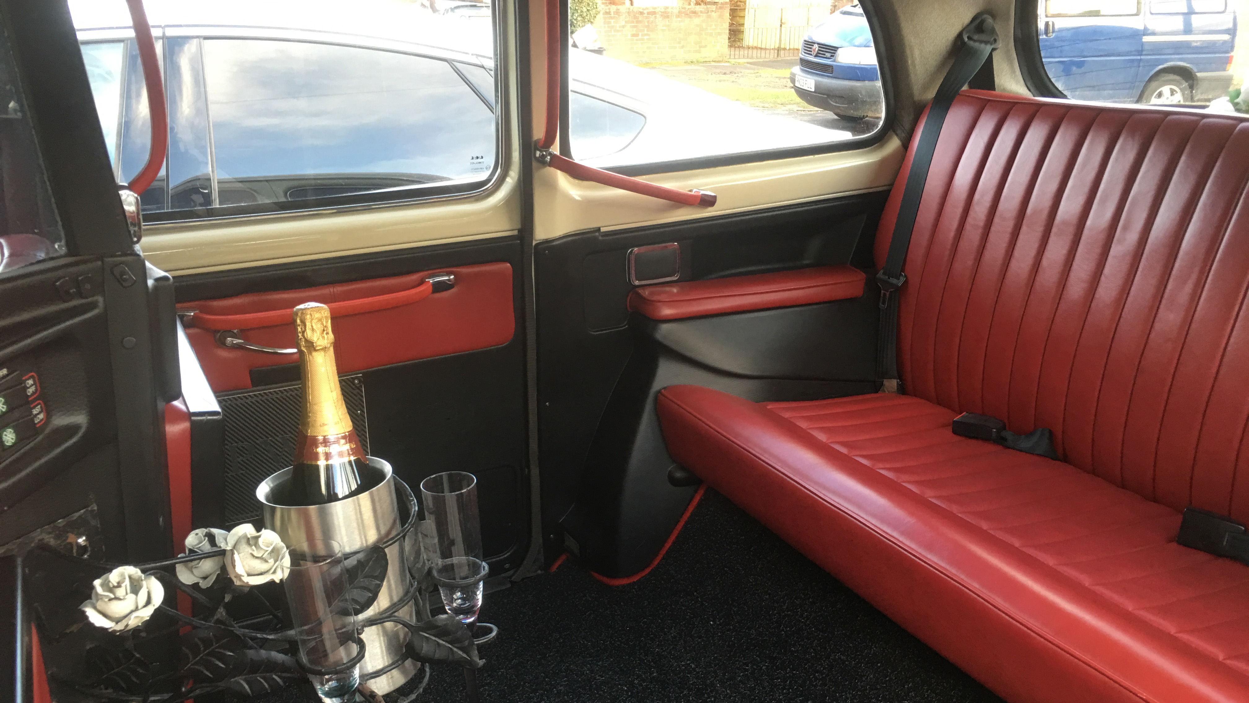 Interior of a classic FX4 taxi cab showing burgundy leather bench seating and traditional cabin layout with drinks hold