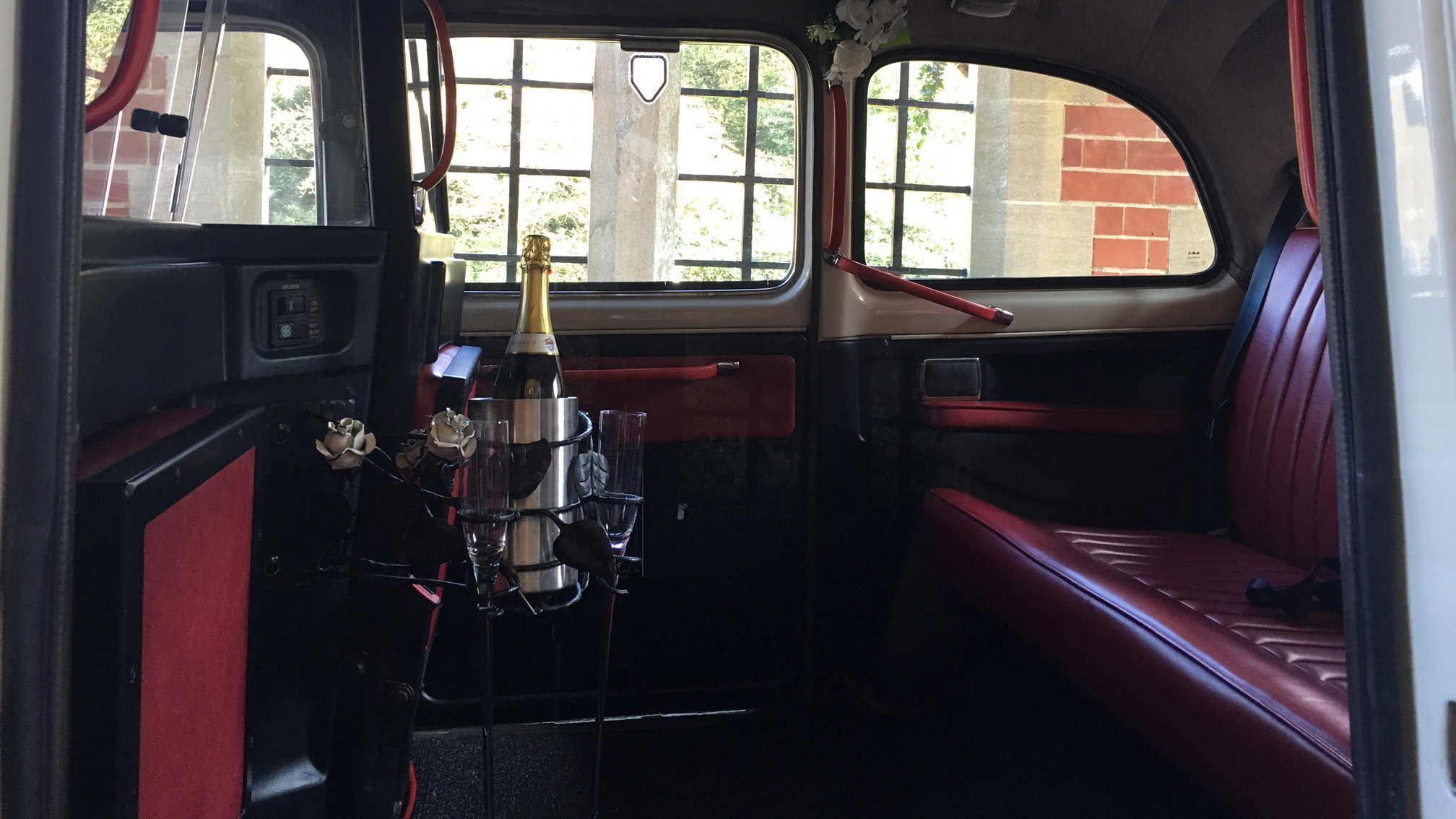 Interior view of a classic FX4 taxi cab with burgundy leather bench seating, facing seats and a polished divider, traditional London taxi layout.