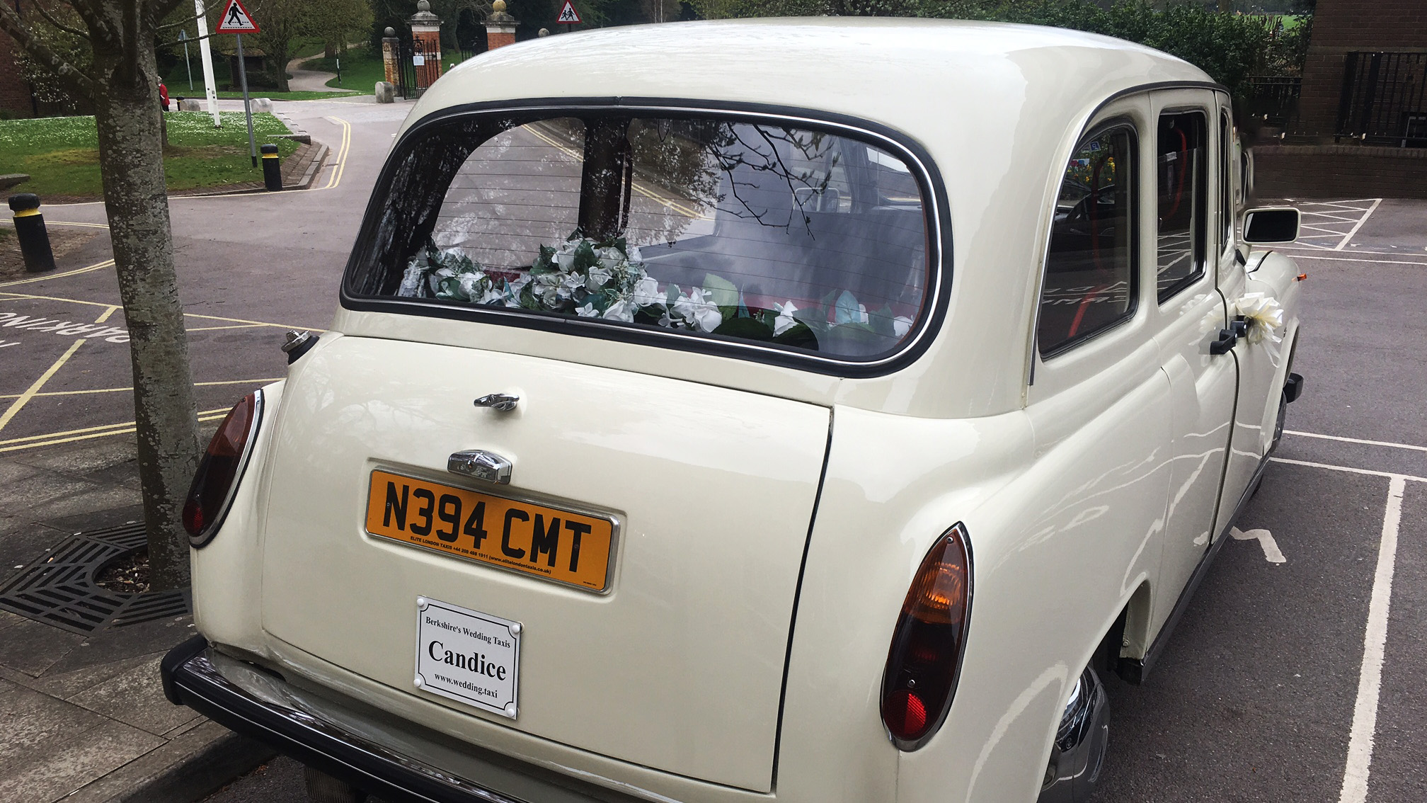 Rear view of a classic taxi cab showing parcel shelf with decorations and registration plate, parked in a car park.