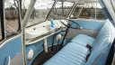 Front interior of a VW split screen campervan with turquoise bench seating, steering wheel and dashboard in classic vintage style.