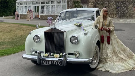Asian Bride standing on the left silver of a classic rolls-roye Silver Cloud