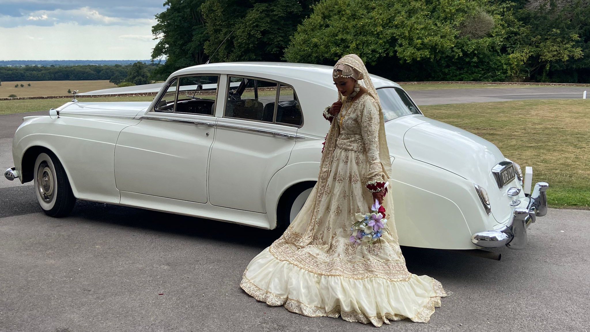 Asian Bride in her authentic wedding dress with a classic rolls-Royce in the background