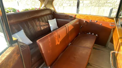 Brown leather interior of Austin Princess limousine with fold-down occasional seats open, showing extended seating layout and polished wood trim