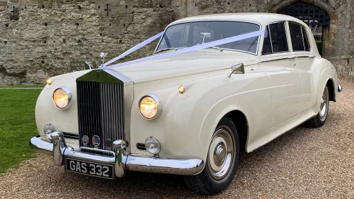 Rolls-Royce Silver Cloud wedding car in Old English White parked on gravel driveway, chrome grille and classic lines visible with countryside setting.
