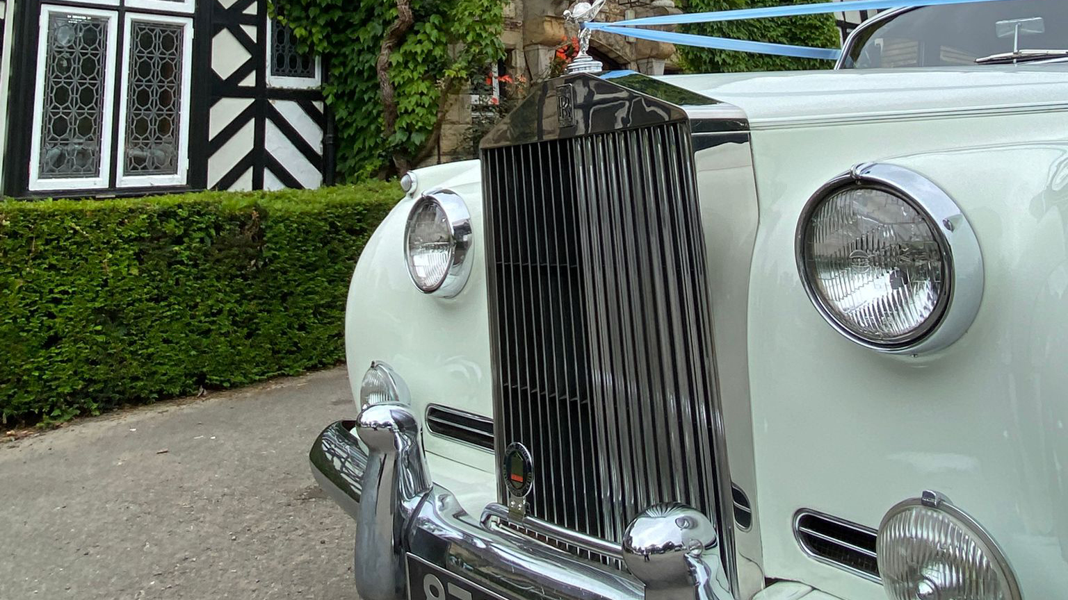 Close-up of Rolls-Royce Silver Cloud chrome grille and Spirit of Ecstasy badge, Old English White bonnet and headlamp detail