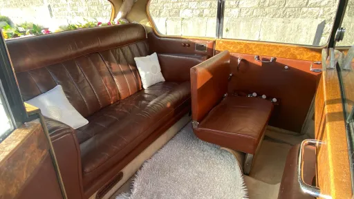 Austin Princess limousine interior in brown leather with one occasional seat folded down, showing partial use of additional seating and spacious cabin