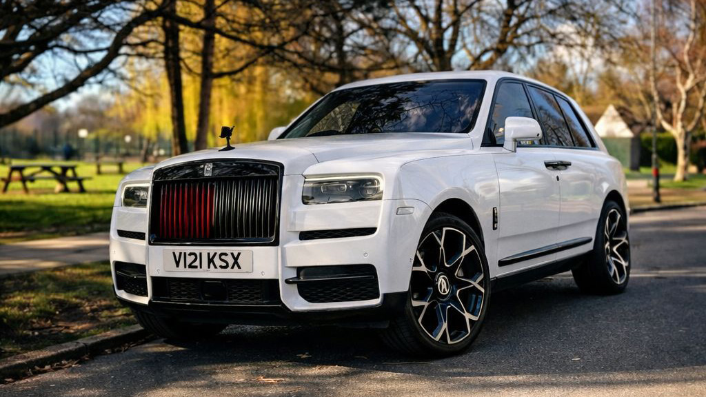 White rolls-Royce Cullinan with large alloy wheels parked in street of London with greenery in the background