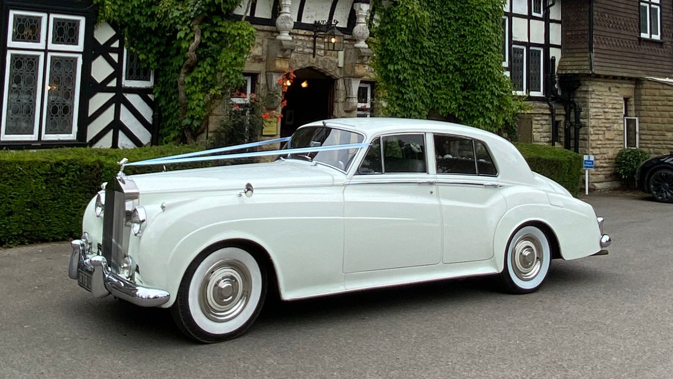 1957 Rolls-Royce Silver Cloud in Old English White showing clean side profile and classic whitewall tyres on driveway