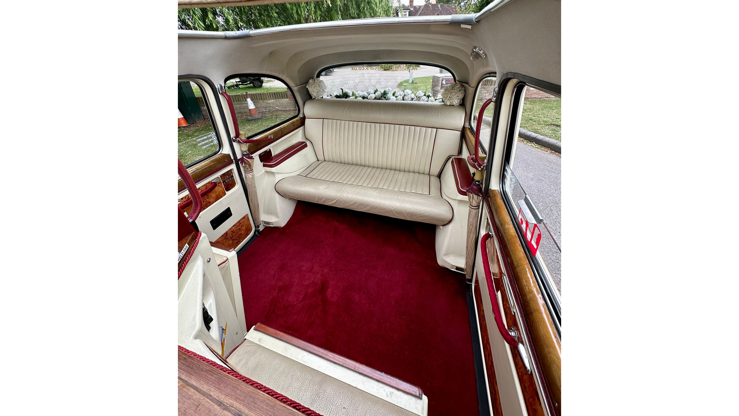 Interior of classic taxi cab showing cream leather seats, deep burgundy carpet and spacious rear cabin.