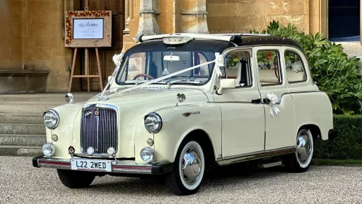 Ivory classic taxi cab for wedding hire with vintage styling, photographed outside a church entrance